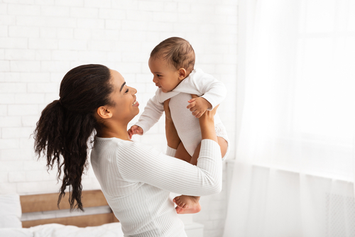 Joyful,African,Mother,Carrying,Baby,Playing,With,Newborn,At,Home